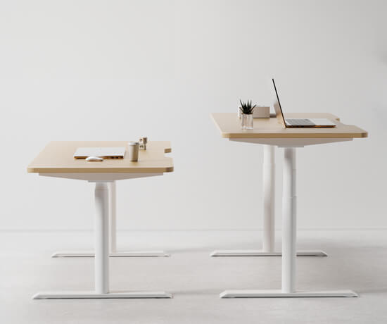 Two Hinomi S1 standing desks in different sizes with a laptop and office supplies.