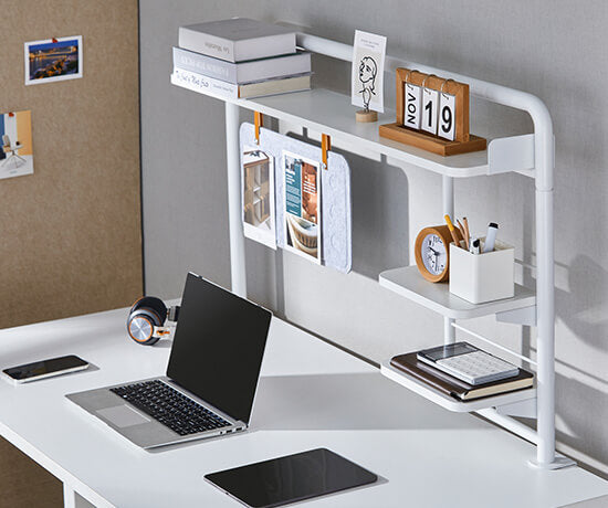 Minimalist home office desk setup with a white organizer shelf and laptop.